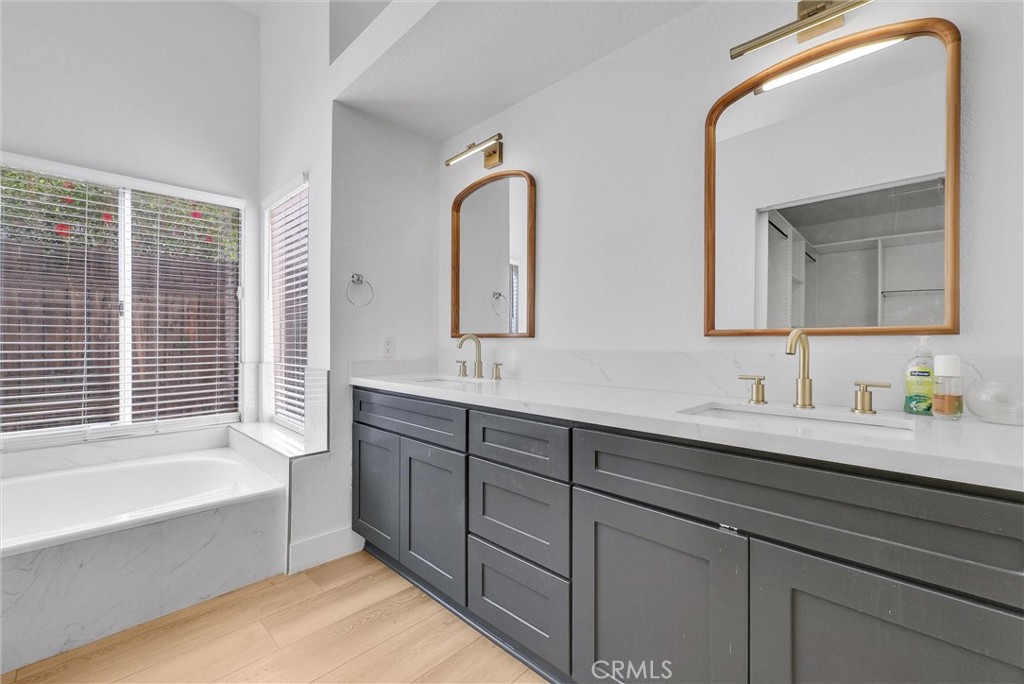 24461 Willow Run Road Moreno Valley, CA 92557 - Photo 15 of 24 a bathroom with a double vanity sink and mirror with bathtub
