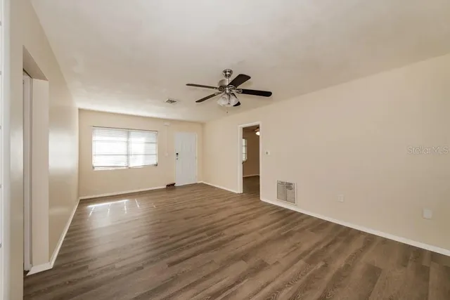 a view of empty room with wooden floor and ceiling fan
