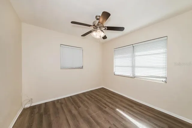 a view of empty room with wooden floor and fan