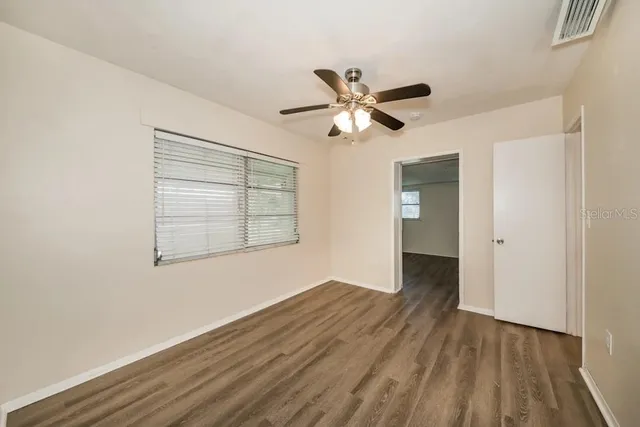 a view of empty room with wooden floor and fan