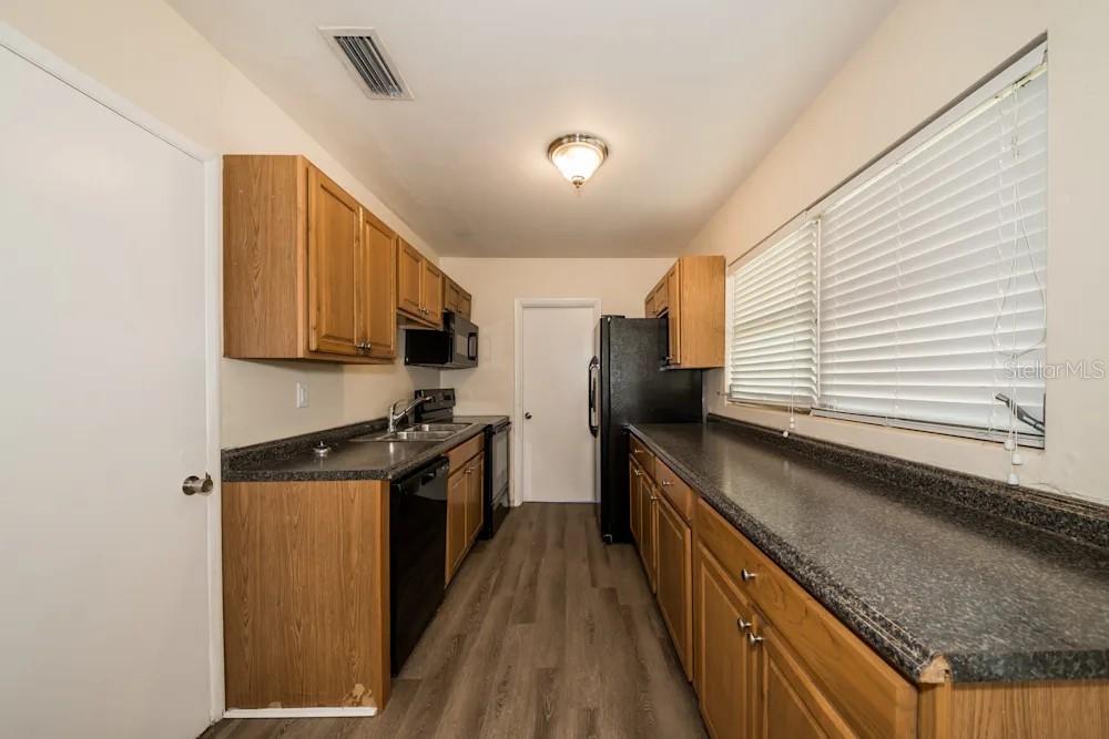 1109 Myrtle Avenue Venice, FL 34285 - Photo 10 of 15 a kitchen with stainless steel appliances a sink dishwasher a stove top oven a refrigerator with wooden floor