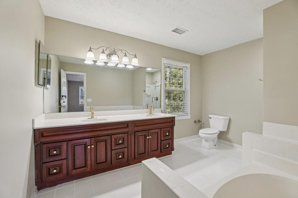 4972 Vermack Road Atlanta, GA 30338 - Photo 15 of 46 a spacious bathroom with a toilet a double vanity sink and a mirror