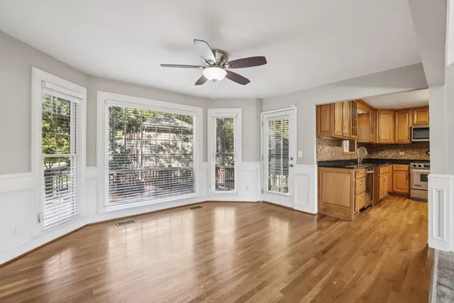 a view of an empty room with wooden floor and a kitchen