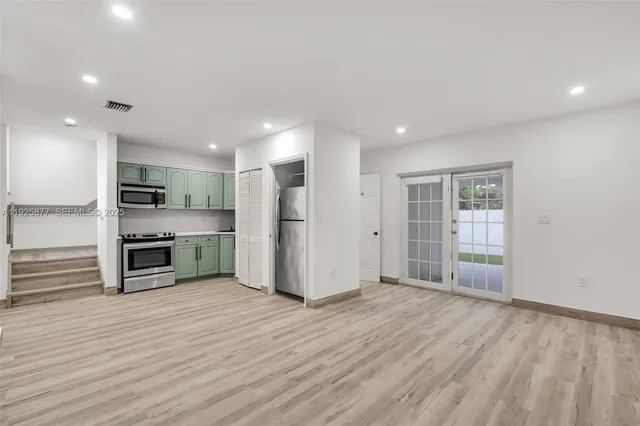 a view of kitchen with stainless steel appliances kitchen island wooden floor and window