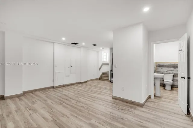 a view of an empty room with wooden floor and a bathroom
