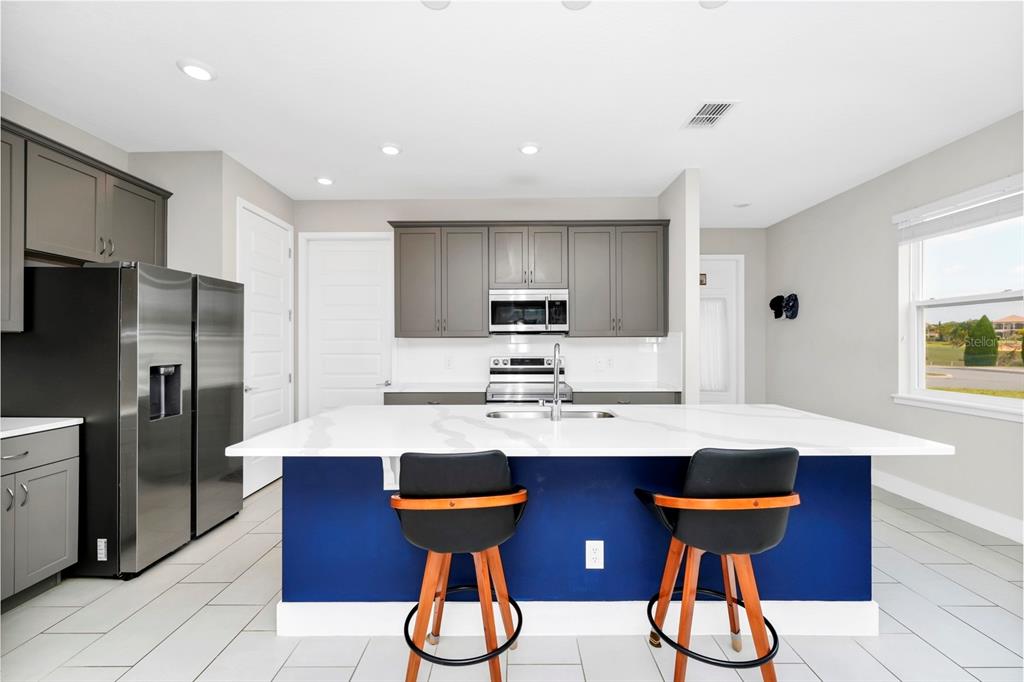743 Driving Range Court Reunion, FL 34747 - Photo 5 of 38 a kitchen with stainless steel appliances kitchen island granite countertop a refrigerator a stove a sink dishwasher with a dining table and chairs