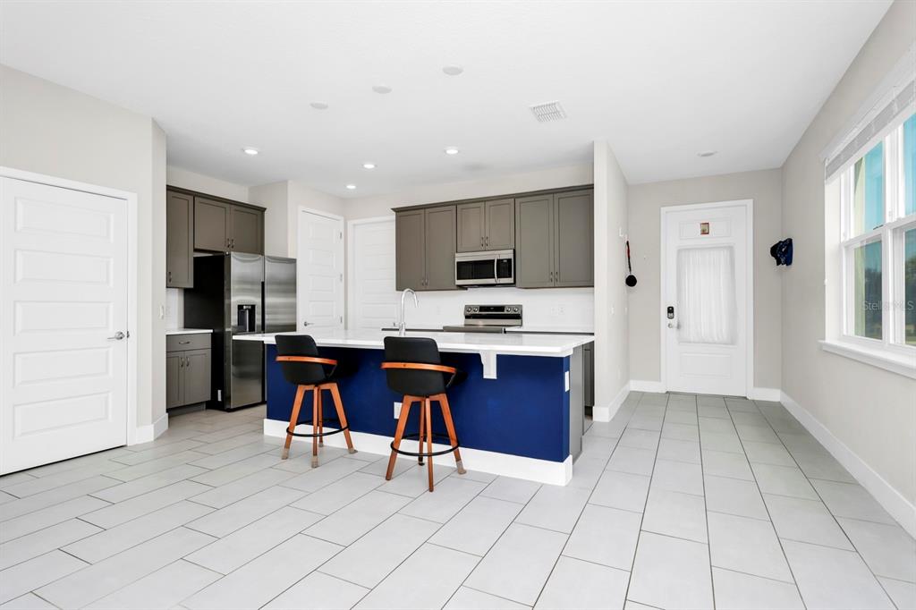 743 Driving Range Court Reunion, FL 34747 - Photo 8 of 38 a view of kitchen with stainless steel appliances granite countertop a stove a sink a refrigerator dining table and chairs