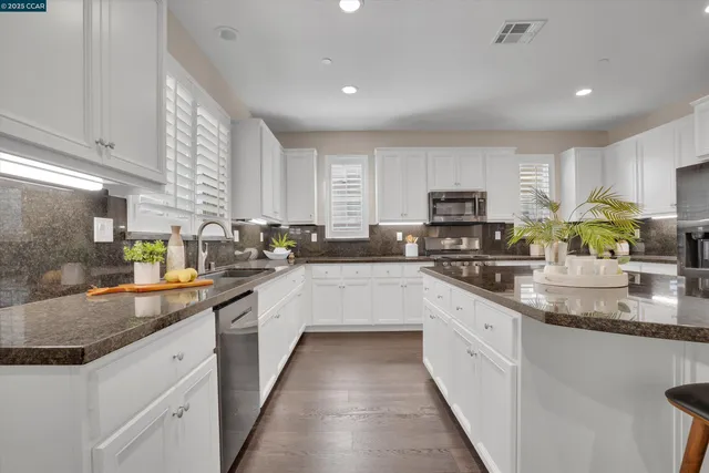 a large kitchen with stainless steel appliances granite countertop a sink counter space cabinets and a large window