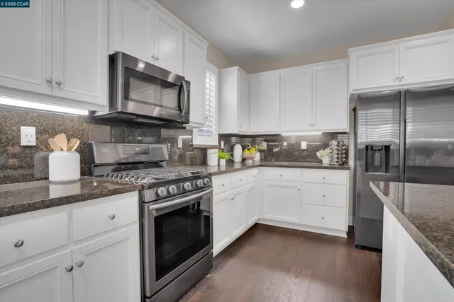 a kitchen with granite countertop white cabinets stainless steel appliances and a sink