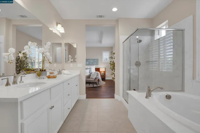a en suite spacious bathroom with a tub double sink and mirrors