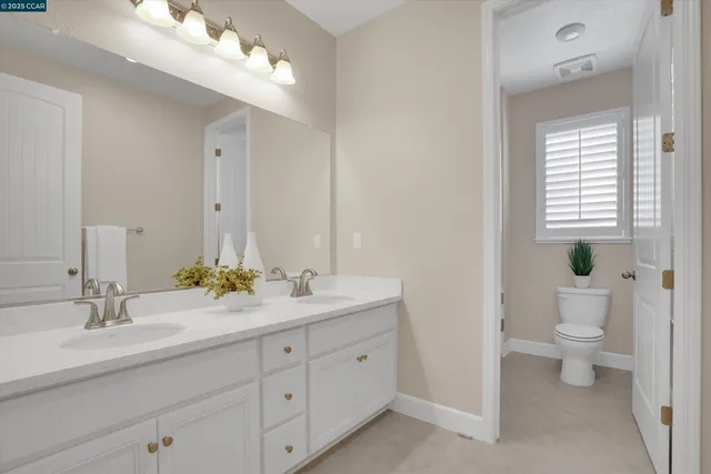 a spacious bathroom with a granite countertop sink a toilet and a mirror