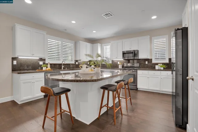 a kitchen with stainless steel appliances granite countertop a stove a sink a microwave a island with a dining table and chairs