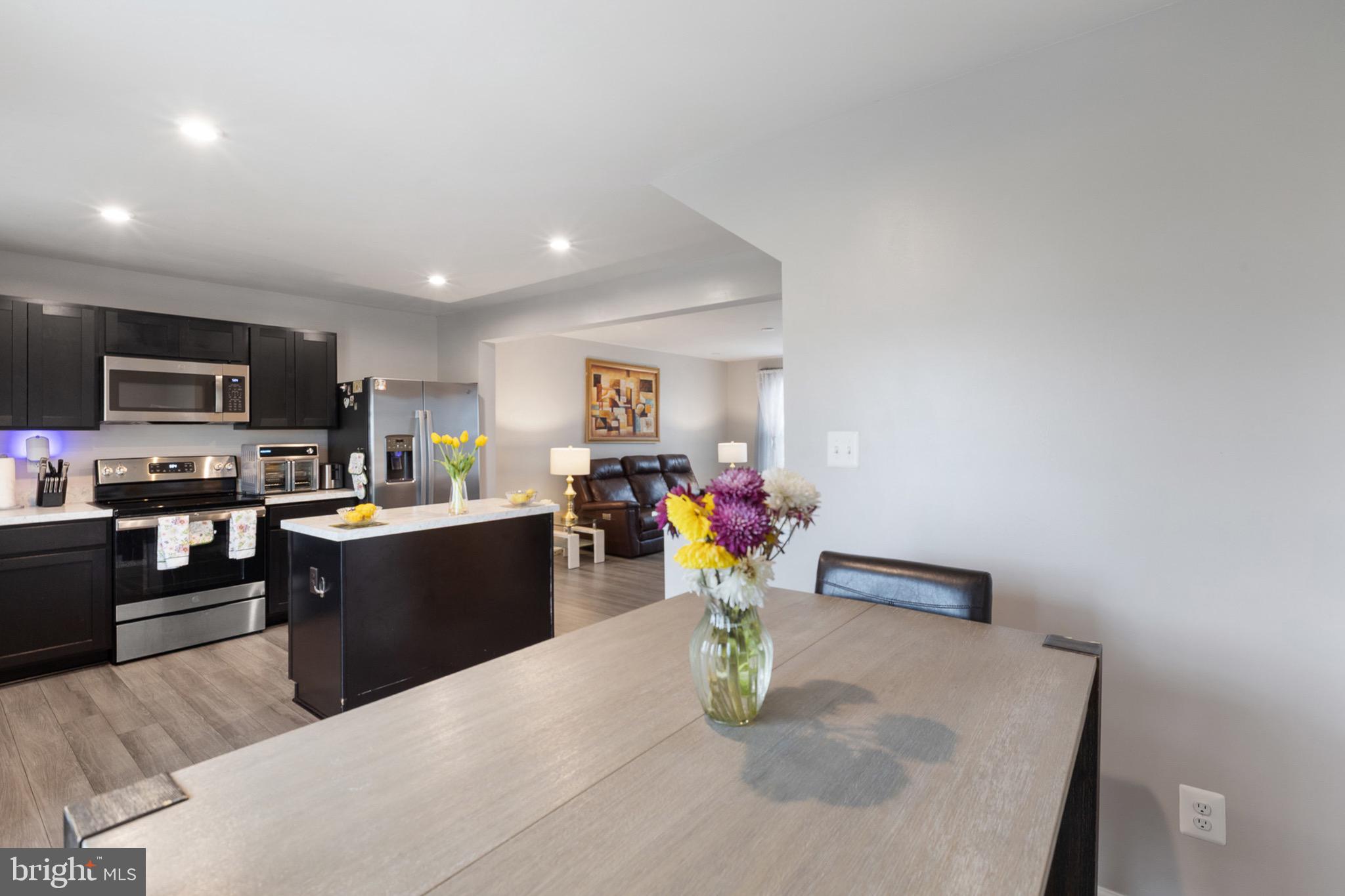 1049 Wickersham Way Middletown, DE 19709 - Photo 18 of 33 a kitchen with stainless steel appliances granite countertop a sink dishwasher a stove top oven a dining table and chairs with wooden floor