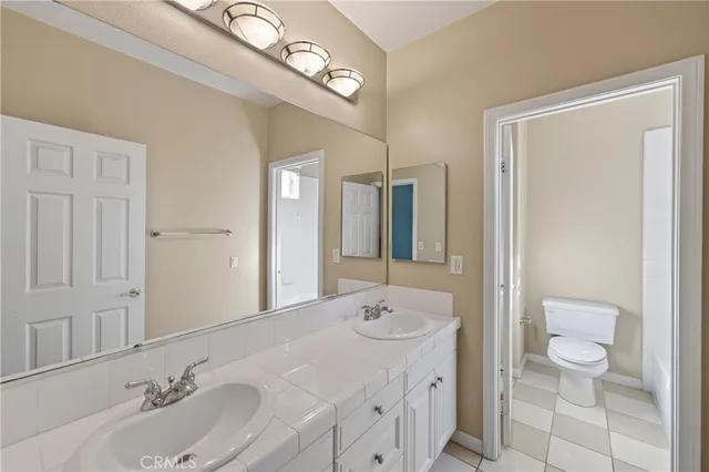 a bathroom with a sink a toilet and a large mirror