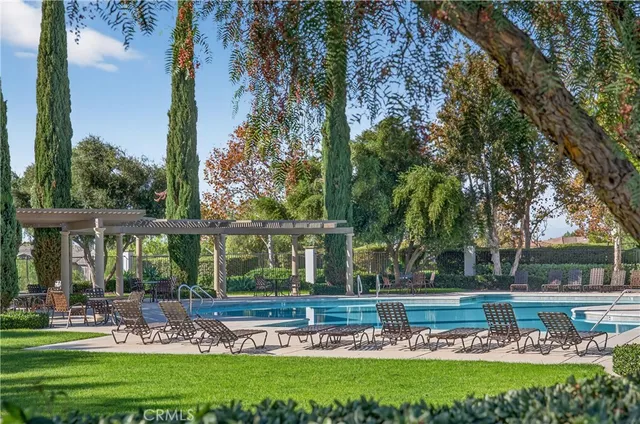 a view of a swimming pool with a bench and trees in the background