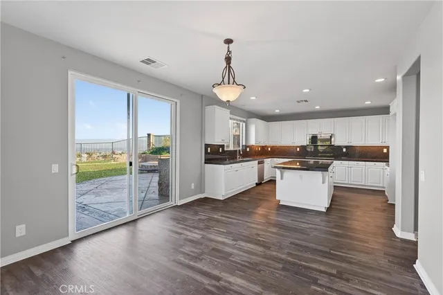 a kitchen with stainless steel appliances kitchen island wooden floors and white cabinets