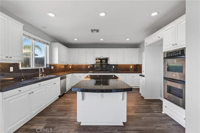 a kitchen with kitchen island granite countertop a stove and a sink