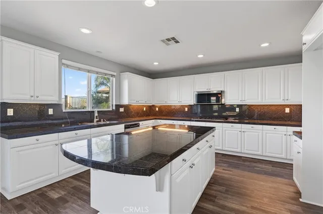 a kitchen with stainless steel appliances granite countertop a sink wooden cabinets granite counter tops and a hard wood floors