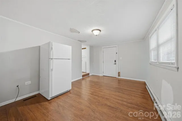 a view of an empty room with wooden floor and a window
