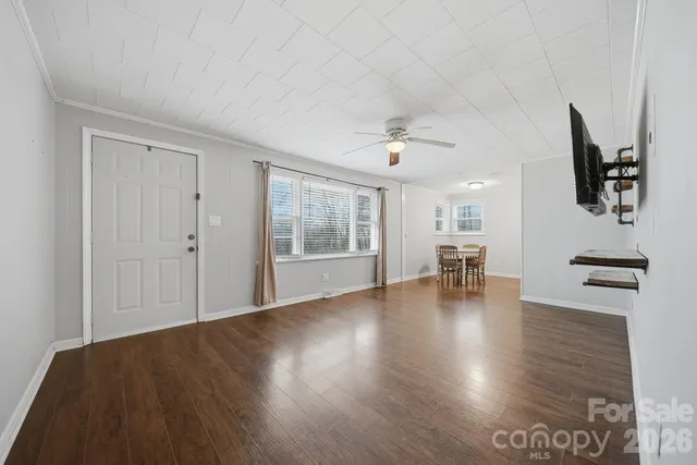 a view of an empty room with wooden floor and a window