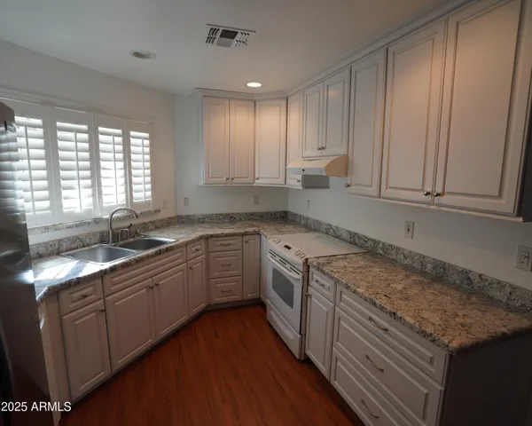 a kitchen with granite countertop cabinets stainless steel appliances a sink and a window