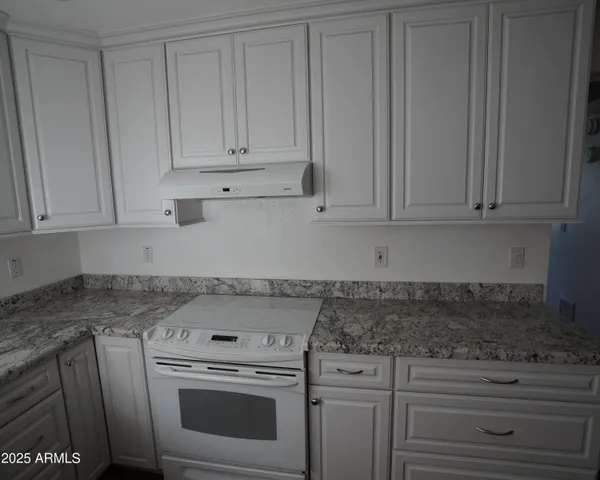 a kitchen with granite countertop white cabinets and white appliances