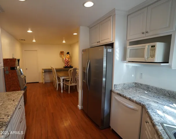 a kitchen with stainless steel appliances granite countertop a refrigerator microwave and wooden floor
