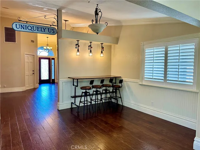 a view of a dining room with wooden floor a chandelier a glass table and chairs