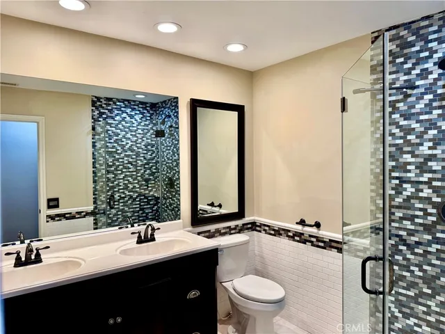 a bathroom with a double vanity sink toilet mirror and shower
