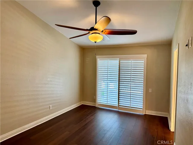a view of an empty room with wooden floor and windows