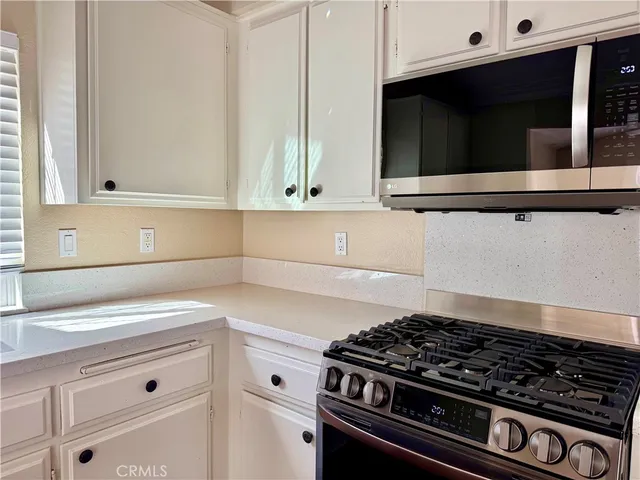 a kitchen with granite countertop white cabinets and stainless steel appliances
