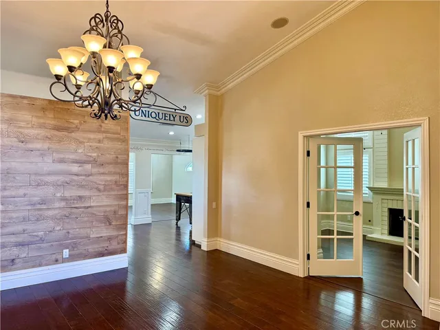a view of a room with wooden floor chandelier and windows