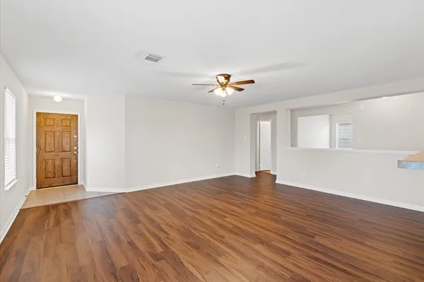 a view of an empty room with wooden floor and window