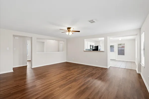a view of a livingroom with wooden floor and kitchen space