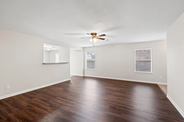 a view of an empty room with a window and wooden floor