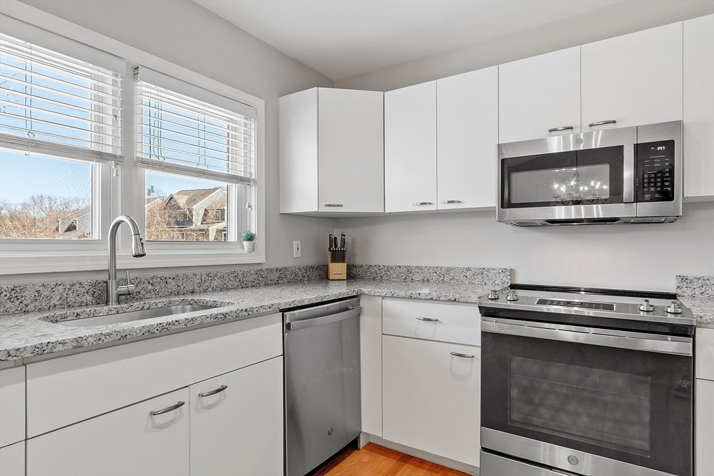 13 Boulderbrook Drive, Unit 13 Peabody, MA 01960 - Photo 6 of 41 a kitchen with stainless steel appliances granite countertop a sink a stove microwave and cabinets