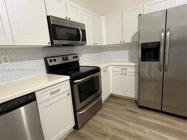 a kitchen with cabinets stainless steel appliances and wooden floor