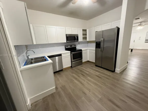 a kitchen with a refrigerator cabinets and wooden floor