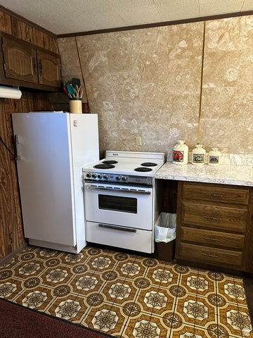 1085 West Elk Road Helper, UT 84526 - Photo 12 of 40 Kitchen featuring wood-finish cabinetry, white appliances, and patterned floor covering
