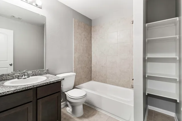 a bathroom with a granite countertop sink a toilet and bathtub