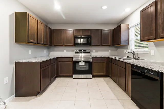 a kitchen with a sink a stove top oven and cabinets