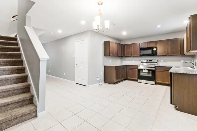 a large white kitchen with stainless steel appliances kitchen island granite countertop a refrigerator and a stove top oven with wooden floor