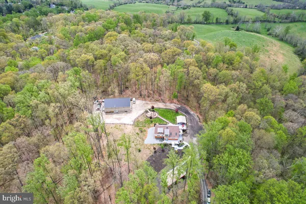an aerial view of residential house with outdoor space and trees all around