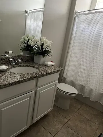 a bathroom with a granite countertop sink a toilet and a mirror