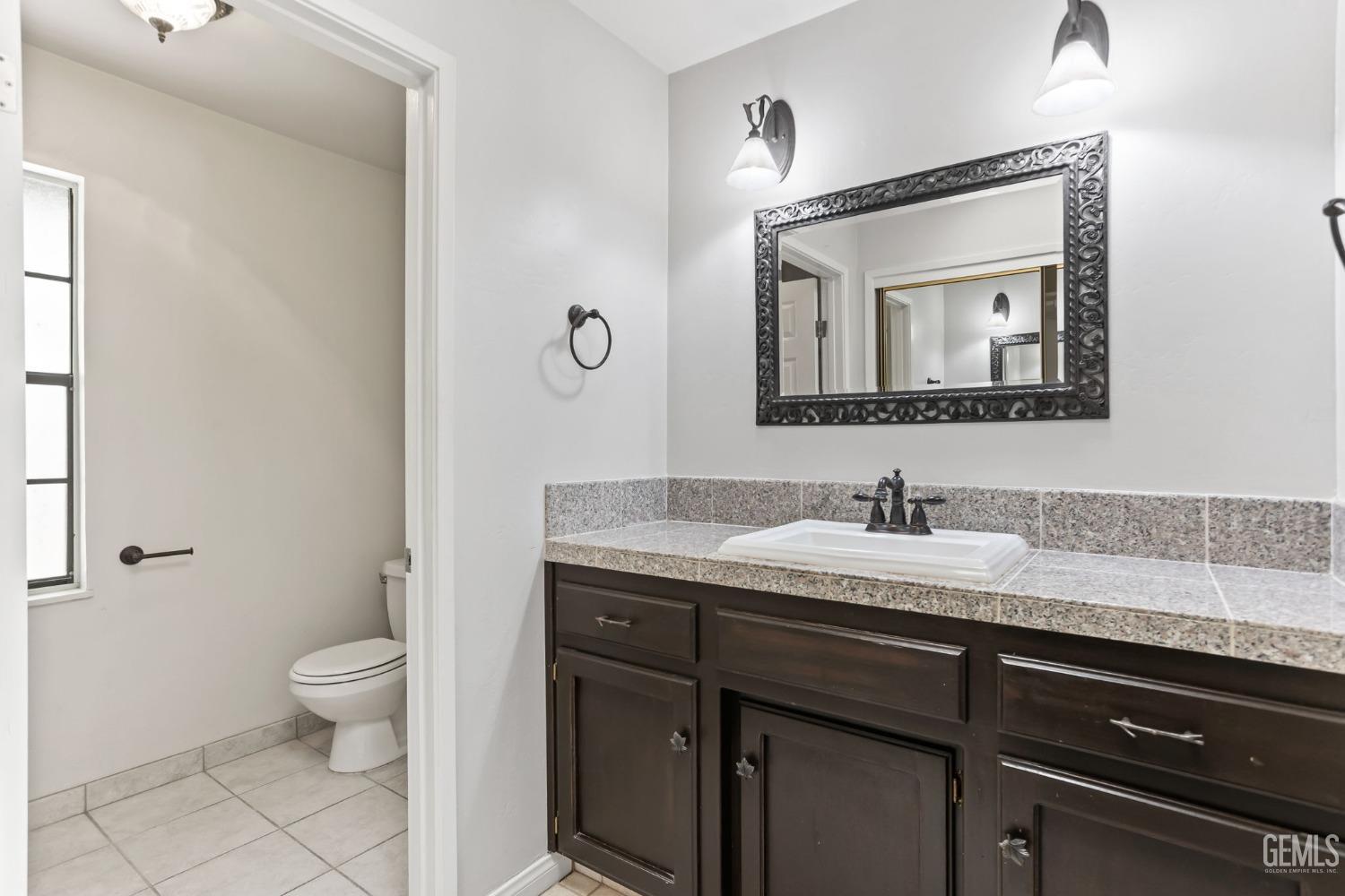 Undisclosed Address Bakersfield, CA 93306 - Photo 37 of 61 a bathroom with a granite countertop sink a toilet and a mirror