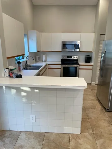 a kitchen with stainless steel appliances a sink a stove a microwave a sink a refrigerator and cabinets