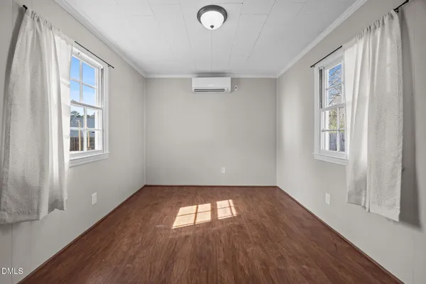 an empty room with wooden floor ceiling fan and windows