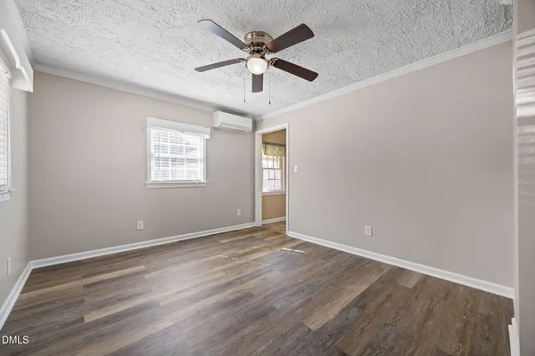 a view of an empty room with a window and wooden floor