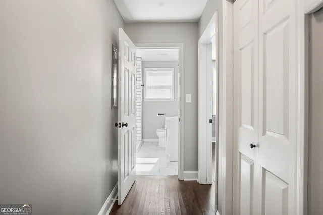 a view of a hallway with wooden floor and a bathroom