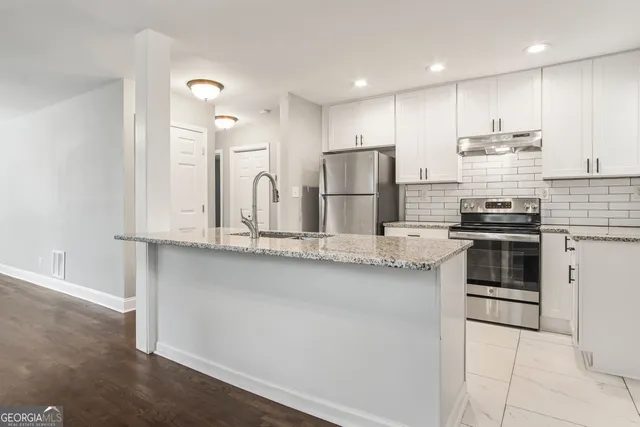a kitchen with stainless steel appliances granite countertop a stove a sink and a refrigerator